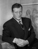 John Wayne wearing a Black Suit while Leaning on a Bag Photo Print - Item # VARCEL709221
