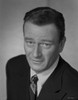 John Wayne Looking at the Camera, wearing a Black Suit and a Tie Photo Print - Item # VARCEL709254