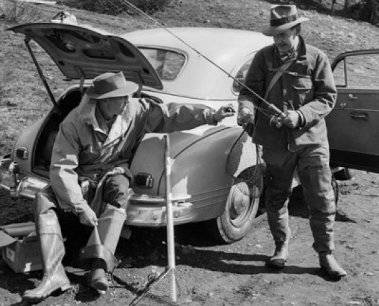 Mid adult man sitting in car trunk with another man standing beside him  holding fishing rod Poster Print - Item # VARSAL25521222