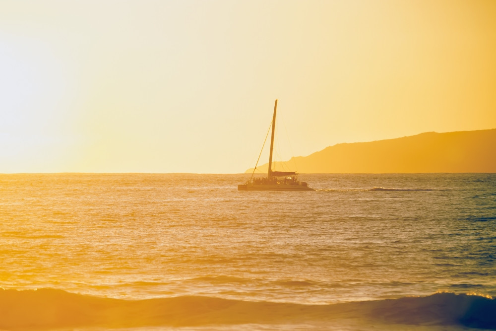 Golden surf visible from Barking Sands Beach with catamaran crossing