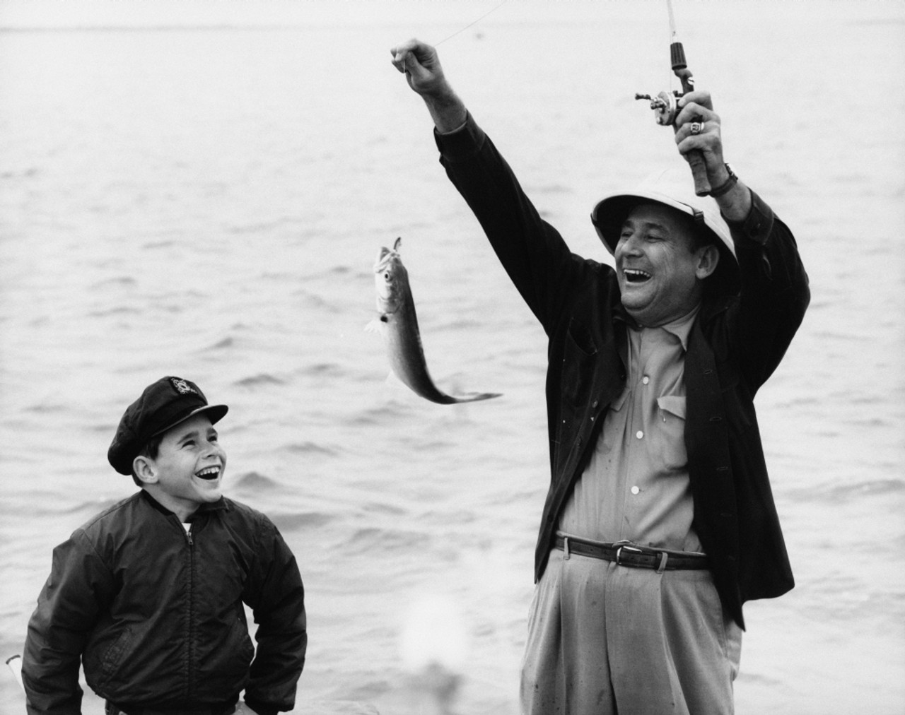 A picture of guy helping his son to hold fish-rod in a right way