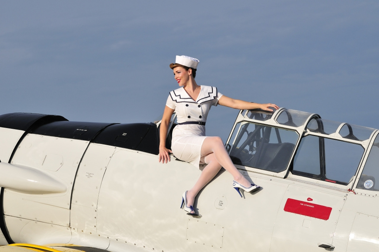 Beautiful 1940's style pin-up girl sitting outside the cockpit of