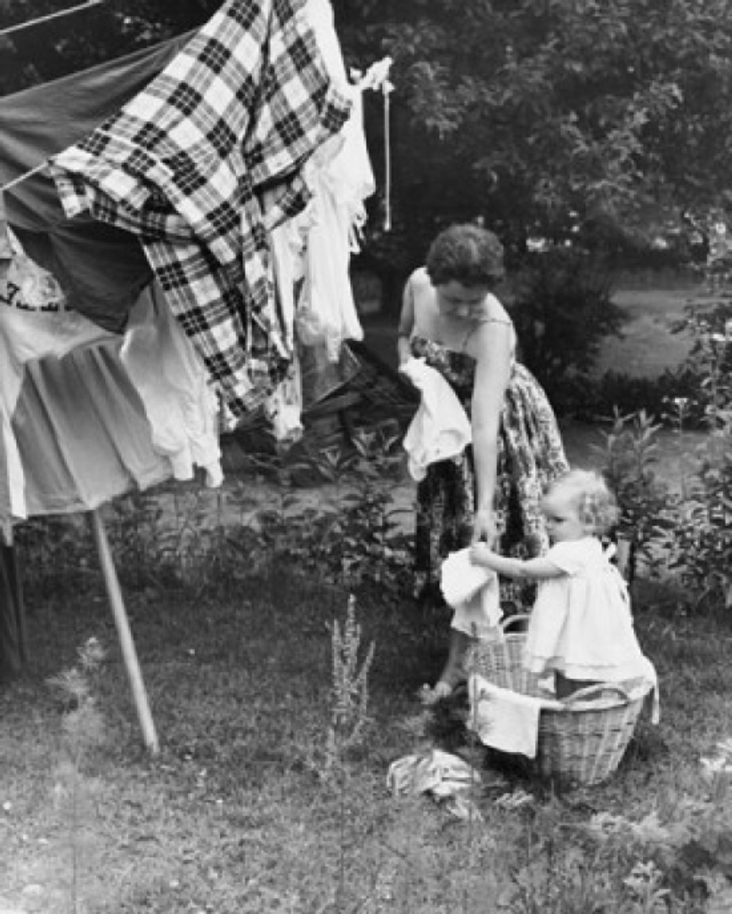 Little girl hanging clothes on clotheslines outside, children's
