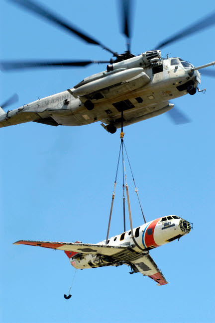 A CH-53 Sea Stallion lifts a HU-25 Guardian Coast Guard aircraft
