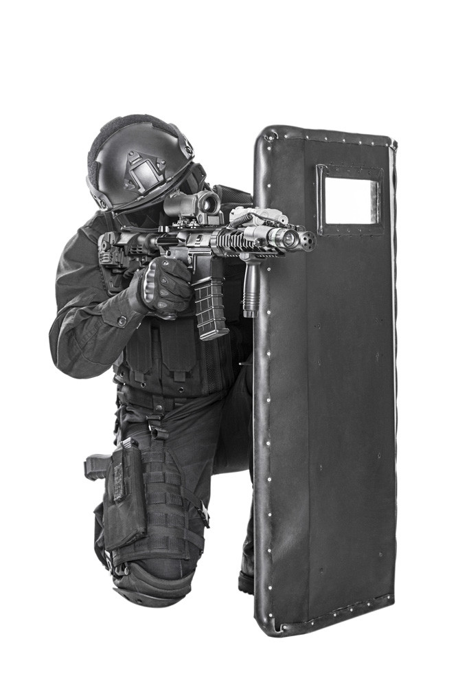 Studio shot of SWAT police special forces with rifle hiding behind