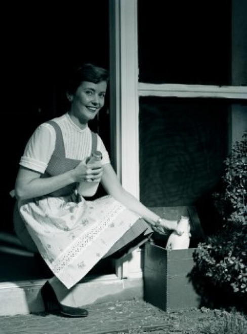 Young woman collecting milk bottles outside home Poster Print - Item # VARSAL255417302