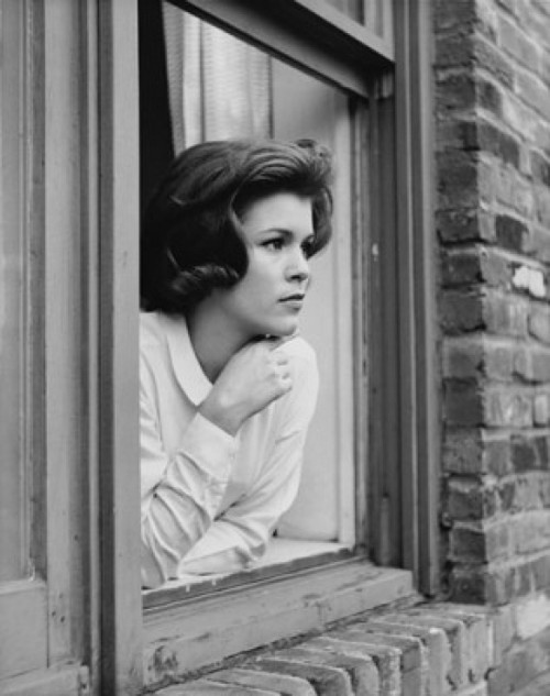 Young woman looking out window Poster Print