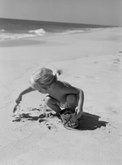 Little girl playing on beach Poster Print