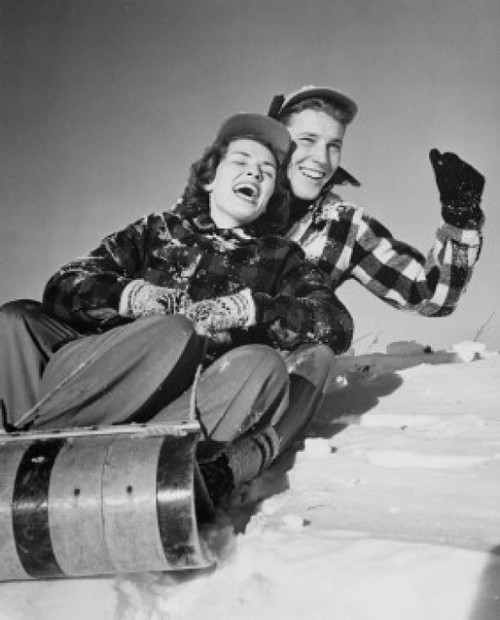 Low angle view of a young couple sliding on a sled Poster Print - Item # VARSAL25518611