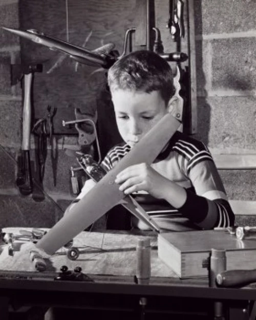 Boy repairing a model airplane Poster Print