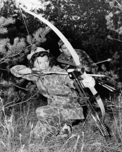 Young woman and a young man hunting with a compound bow in a forest Poster Print - Item # VARSAL25524048
