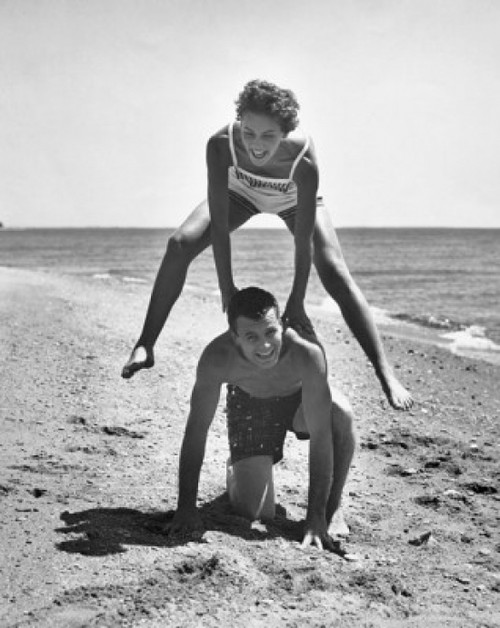 Young couple playing leapfrog on the beach Poster Print - Item # VARSAL2558794