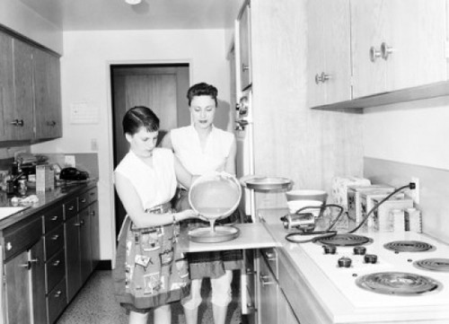 Teenage girl preparing food in the kitchen with her mother standing beside her Poster Print - Item # VARSAL25535405