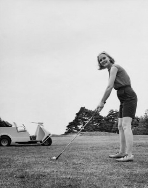 Young woman playing golf on a golf course Poster Print
