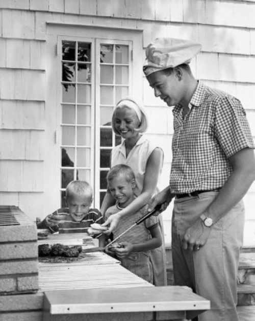 Side profile of a mid adult man cooking food with his wife and two children standing beside him Poster Print - Item # VARSAL2554577