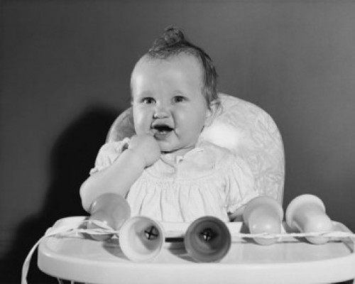 Baby girl sitting in a high chair with her finger in her mouth Poster Print - Item # VARSAL2559708