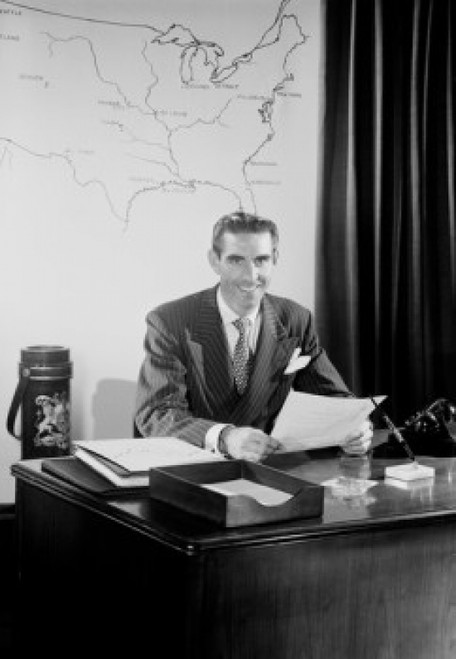 Mid adult man sitting at desk in office Poster Print - Item # VARSAL255422331