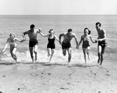 Three young couples running on beach Poster Print