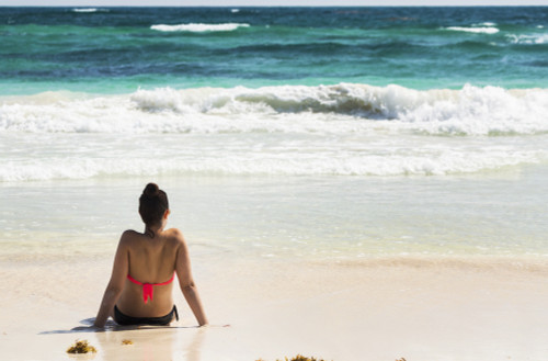 Young woman sitting on sandy beach in water looking out at waves coming in and blue sky; Akumal, Quintana Roo, Mexico PosterPrint - Item # VARDPI12269299