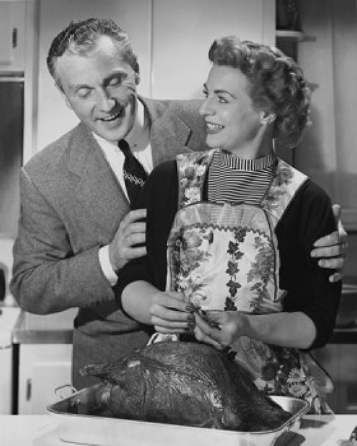 Mid adult man woman preparing a turkey and a mid adult man holding her from behind Poster Print - Item # VARSAL25536201B