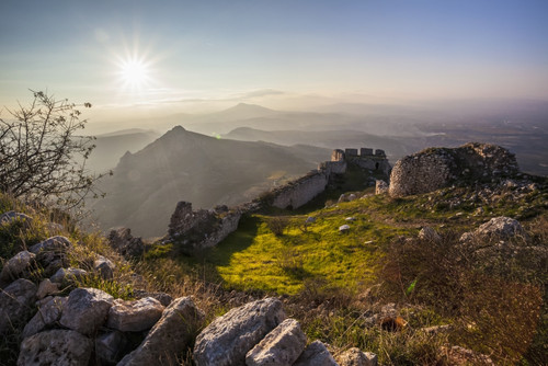 Ruins of a stone wall and buildings with a sunburst and mountains; Corinth, Greece PosterPrint - Item # VARDPI12286929