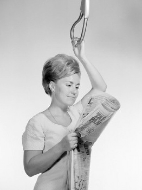 Young woman reading newspaper while holding handle Poster Print - Item # VARSAL255417676