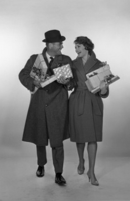 Mid adult couple laughing  looking at each other and holding gifts  studio shot Poster Print - Item # VARSAL255417361