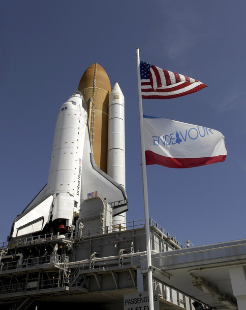 At the Kennedy Space Center in Florida, flags swing in the breeze as space shuttle Endeavour approaches Launch Pad 39A. Poster Print - Item # VARPSTSTK202755S