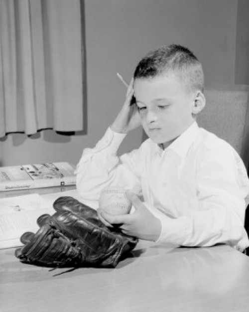 USA  Boy with baseball and glove doing homework Poster Print