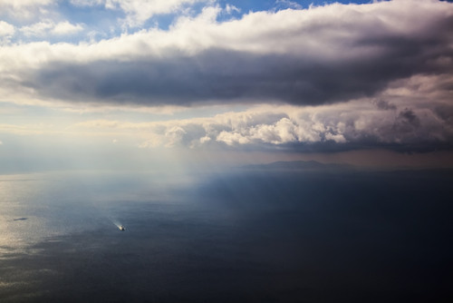 A lone boat on the Aegean sea under a cloudy sky and distant view of the coastline; Greece PosterPrint - Item # VARDPI12286568
