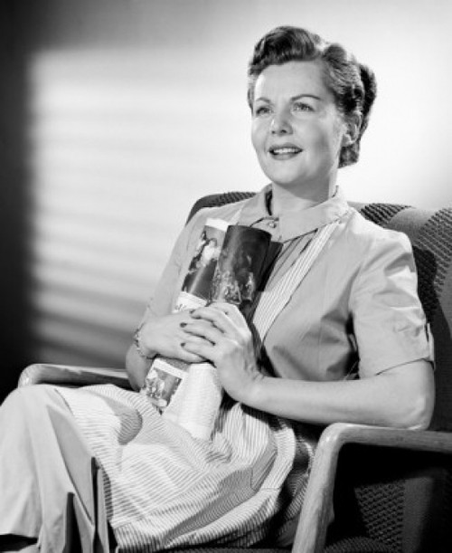 Mid-adult woman contemplation in armchair  holding rolled-up magazine Poster Print - Item # VARSAL25542002