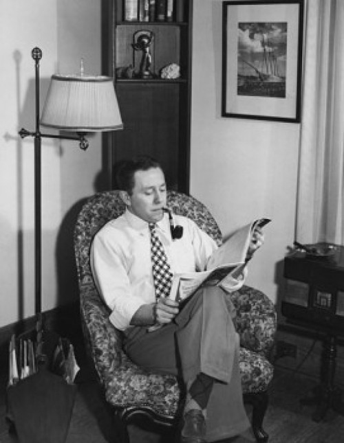 Young man reading a magazine in an armchair Poster Print - Item # VARSAL25536511