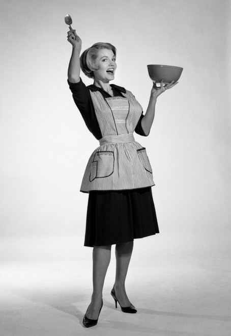 1960s Excited Woman Housewife In Apron Black Dress And High Heels Looking At Camera Holding Up Mixing Bowl And Kitchen - Item # PPI179112LARGE