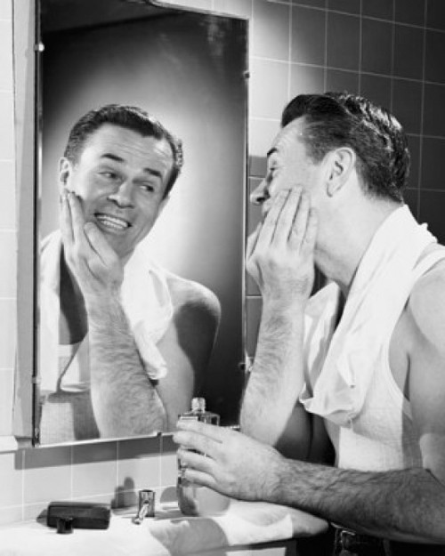 Young man applying aftershave to his face Poster Print - Item # VARSAL25527360
