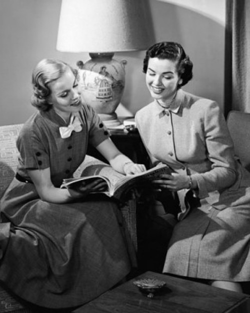 Two young women sitting in armchairs and looking at a book Poster Print - Item # VARSAL25528882B