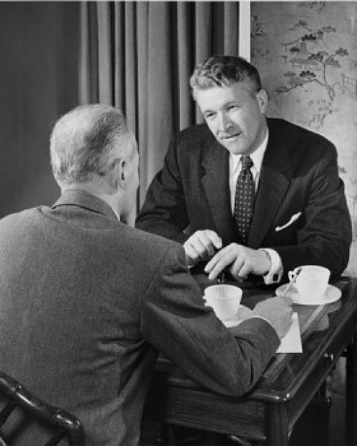 Two businessmen talking indoors Poster Print