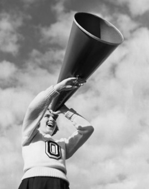 Low angle view of a female cheerleader holding a megaphone and laughing Poster Print - Item # VARSAL25515939