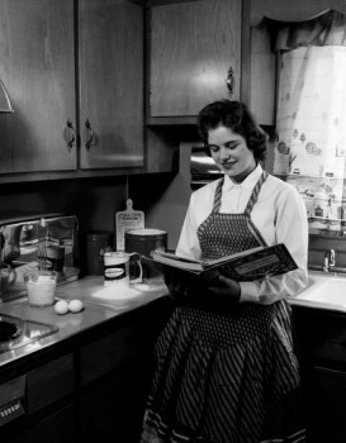 Young woman reading recipe book in kitchen Poster Print - Item # VARSAL25536221