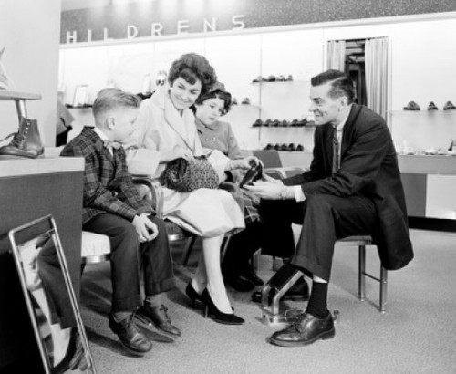 Shop assistant showing boy shoe to mother with son and daughter Poster Print - Item # VARSAL255417915B
