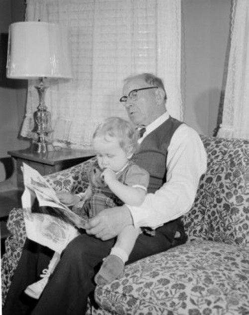 Girl reading newspaper with grandfather in living room Poster Print - Item # VARSAL255422172