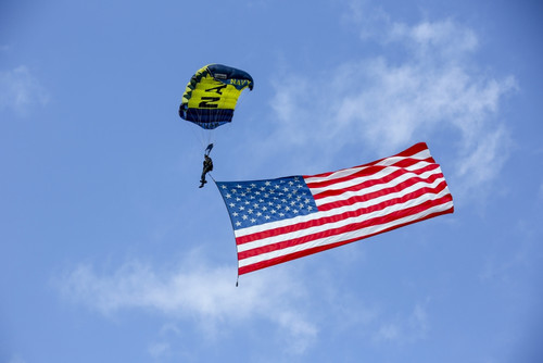 Member of the U.S. Navy Parachute Team, the Leap Frogs, flies the American Flag as he prepares to land at the demonstration ground at the National Navy SEAL Museum in Fort Pierce, Florida Poster Print - Item # VARPSTWOD100194M