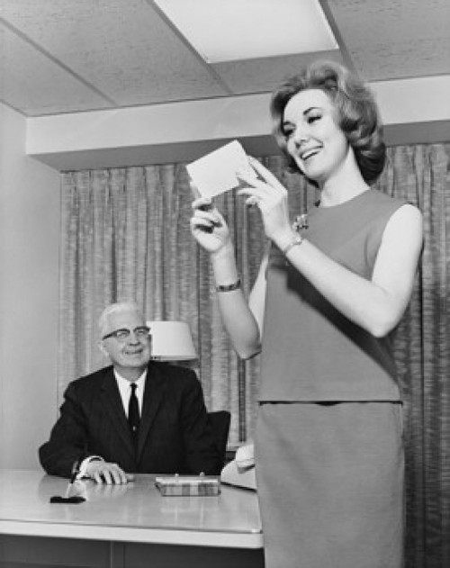 Businessman looking at his secretary holding a check and smiling in an office Poster Print