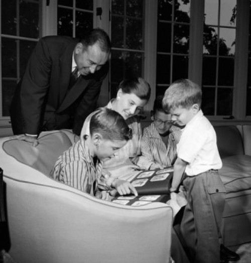 Family with three boys viewing photograph album in living room Poster Print - Item # VARSAL255417579