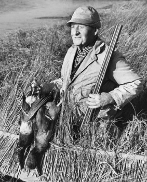 Male hunter holding two dead ducks and a rifle in a field Poster Print - Item # VARSAL25524387