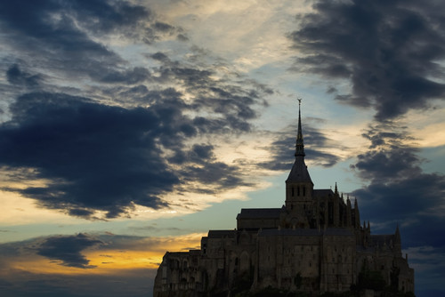 Silhouette of large stone Abbey perched on rocky hill with dramatic clouds at sunset; Mont St. Michel, Brittany, France PosterPrint - Item # VARDPI12282602