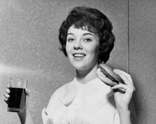 Portrait of a young woman holding a hamburger and a drink Poster Print - Item # VARSAL25512646