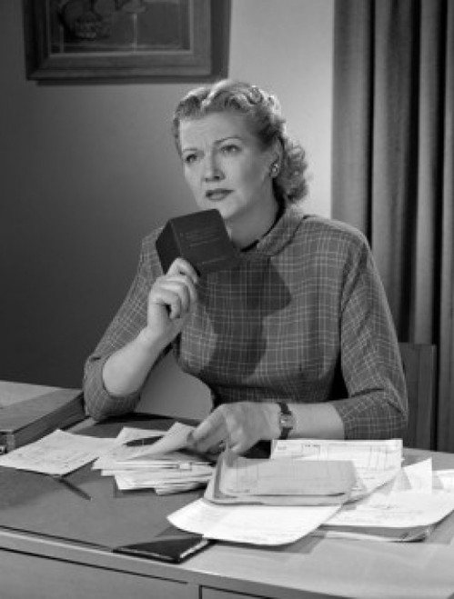 Woman sitting at desk holding booklet Poster Print - Item # VARSAL25527459