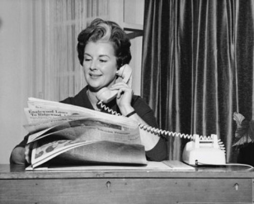 Businesswoman talking on the telephone and holding a newspaper in an office Poster Print - Item # VARSAL25516882