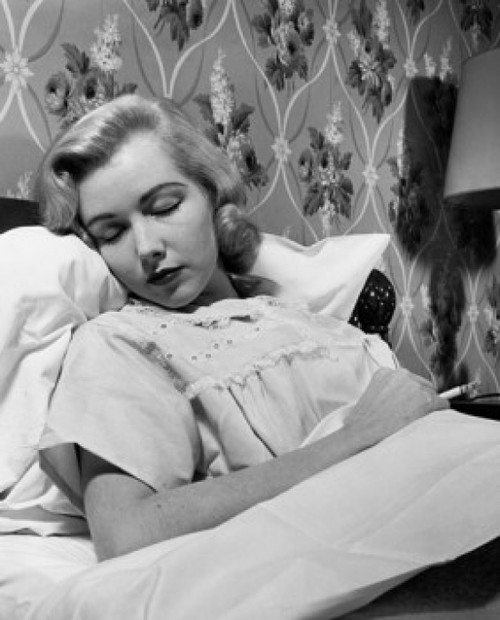 Young woman sleeping in the bed and holding a cigarette Poster Print - Item # VARSAL25544606