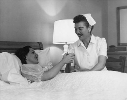 Female nurse giving a glass of water to a young woman Poster Print - Item # VARSAL25526321